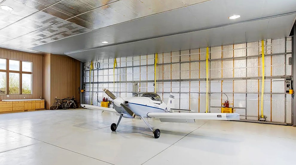 Schweiss liftstrap bifold hangar home door installed on hangar home in Colorado viewed from inside behind plane Schweiss liftstrap bifold hangar home door installed on hangar home in Colorado viewed from inside behind plane