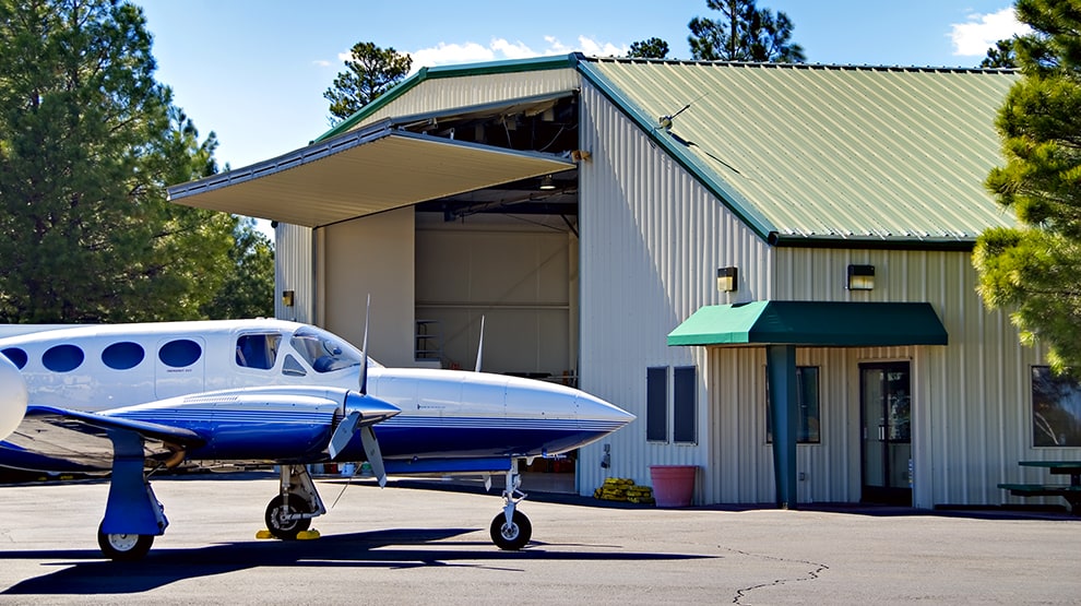 Plane parked in front of tall hangar equipped with Schweiss bifold hangar door shown open Plane parked in front of tall hangar equipped with Schweiss bifold hangar door shown open