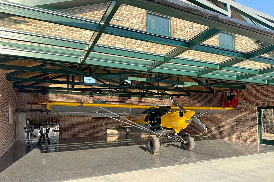 Front view of Don Smith Jr's plane parked inside his backyard hangar fitted with Schweiss glass hydraulic door shown open Front view of Don Smith Jr's plane parked inside his backyard hangar fitted with Schweiss glass hydraulic door shown open