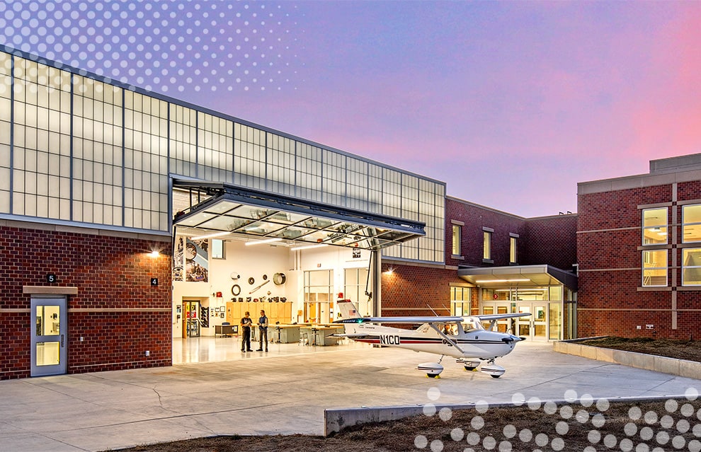 Exterior view from left of Schweiss glass bifold door installed on Lincoln North Star High School, a plane parked outside of it Exterior view from left of Schweiss glass bifold door installed on Lincoln North Star High School, a plane parked outside of it