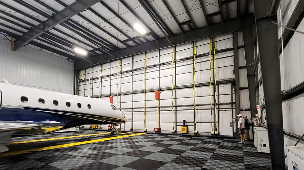 Interior view of hangar fitted with Schweiss bifold lift strap door shown closed and a parked jet inside in Florida Interior view of hangar fitted with Schweiss bifold lift strap door shown closed and a parked jet inside in Florida