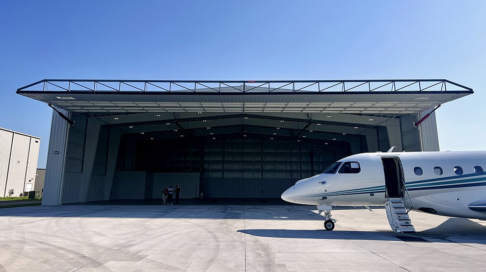Head on angle of a Schweiss hydraulic door installed on Lanz Hangar with a corporate jet parked off to the right Head on angle of a Schweiss hydraulic door installed on Lanz Hangar with a corporate jet parked off to the right