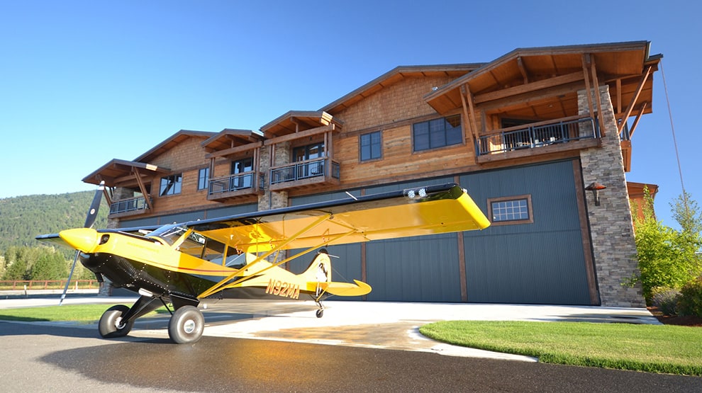 Yellow Husky airplane parked outside of hangar home at Alpine airpark fitted with Schweiss hangar home door Yellow Husky airplane parked outside of hangar home at Alpine airpark fitted with Schweiss hangar home door