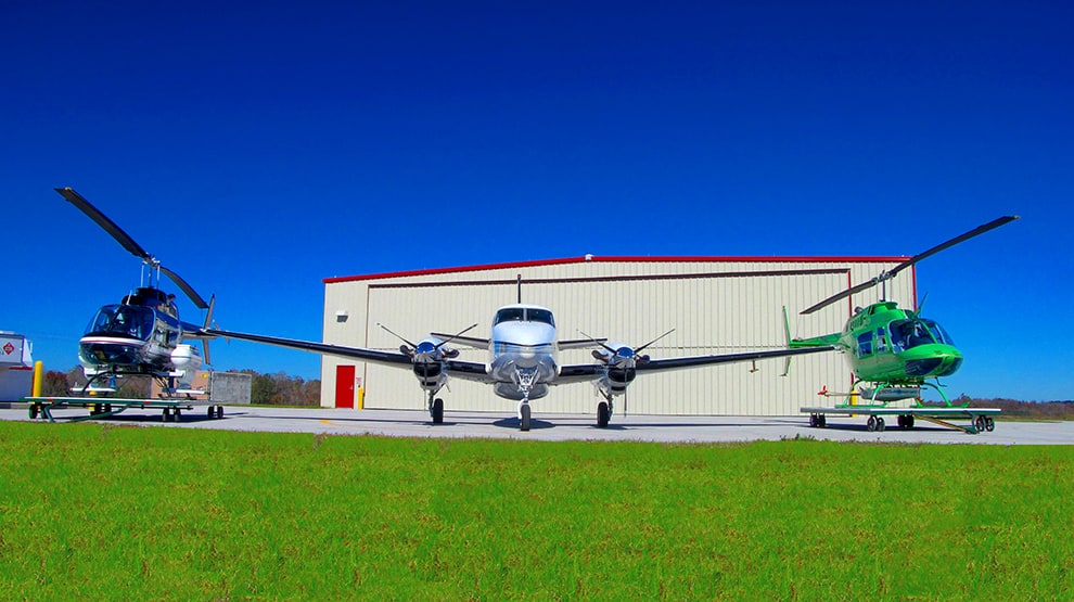 Two helicopters and a plane parked in front of a hangar fitted with a Schweiss bifold door Two helicopters and a plane parked in front of a hangar fitted with a Schweiss bifold door