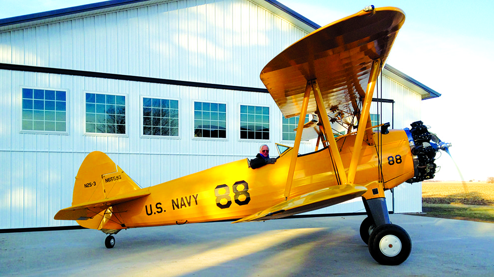 Old US Navy plane parked outside of Burroughs farm hangar fitted with Schweiss bifold door Old US Navy plane parked outside of Burroughs farm hangar fitted with Schweiss bifold door