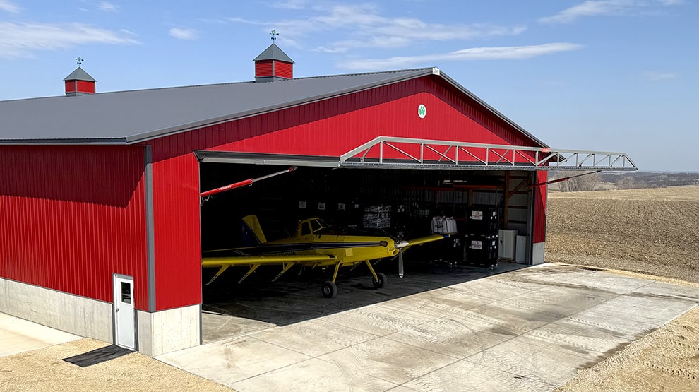 Yellow crop duster plane parked inside of hangar fitted with Schweiss hydraulic hangar door Yellow crop duster plane parked inside of hangar fitted with Schweiss hydraulic hangar door