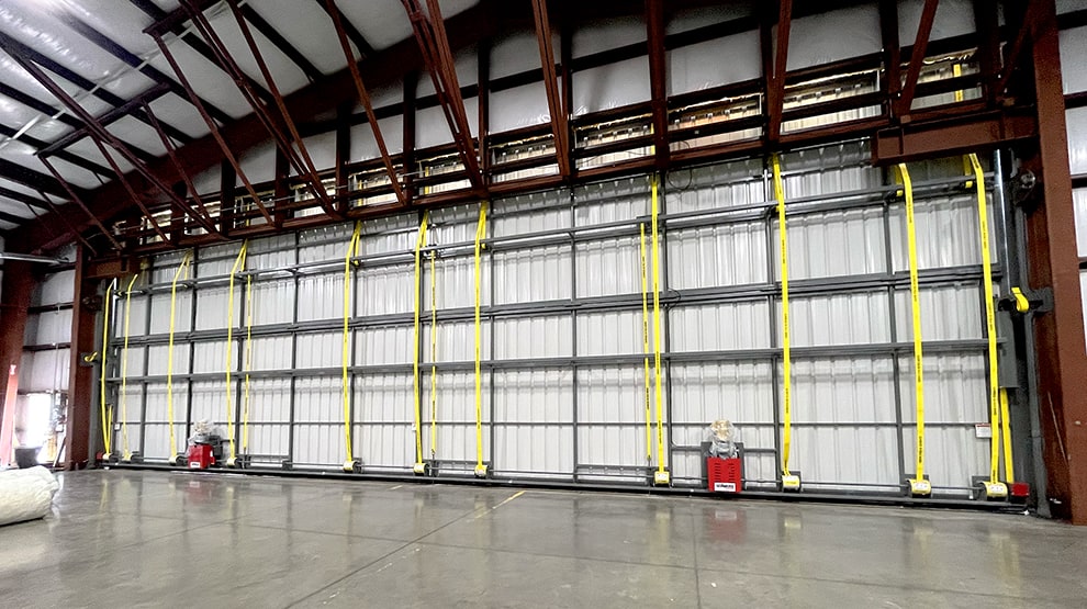 Interior view of Schweiss bifold door with yellow lift straps and bottom drive motors installed on hangar Interior view of Schweiss bifold door with yellow lift straps and bottom drive motors installed on hangar