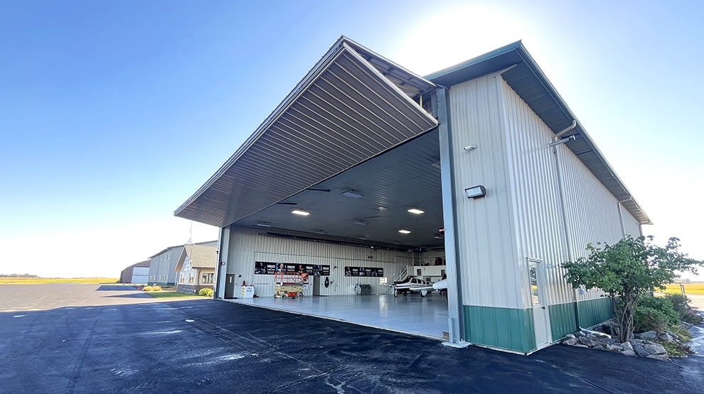 Exterior view of Schweiss bifold door installed on a hangar with a plane or two parked inside Exterior view of Schweiss bifold door installed on a hangar with a plane or two parked inside