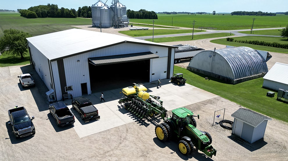 Multiple vehicles and a tractor with trailer parked outside a machine shed fitted with Schweiss bifold machine shed door Multiple vehicles and a tractor with trailer parked outside a machine shed fitted with Schweiss bifold machine shed door