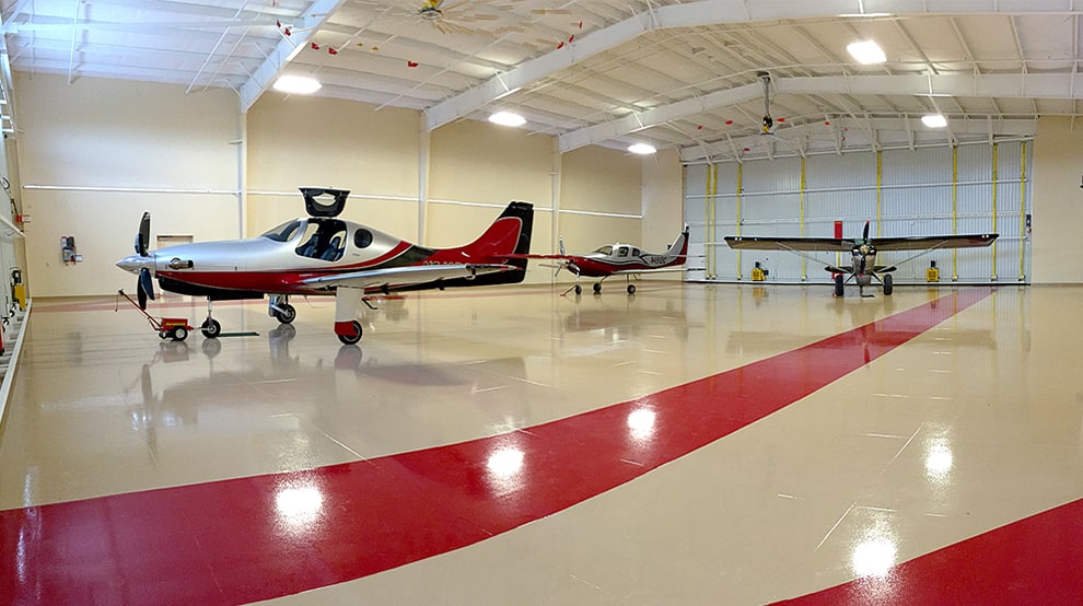 Three airplanes parked inside hangar that is fitted with multiple Schweiss liftstrap bifold doors that are shown closed Three airplanes parked inside hangar that is fitted with multiple Schweiss liftstrap bifold doors that are shown closed