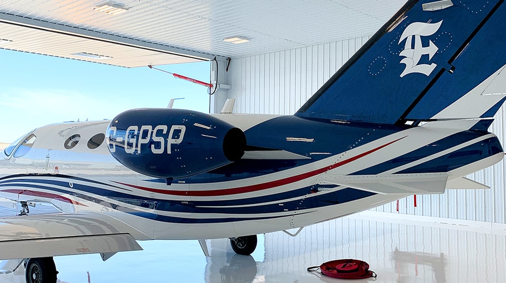 Large passenger jet parked inside of all white hangar fitted with a opened Schweiss hydraulic hangar door Large passenger jet parked inside of all white hangar fitted with a opened Schweiss hydraulic hangar door