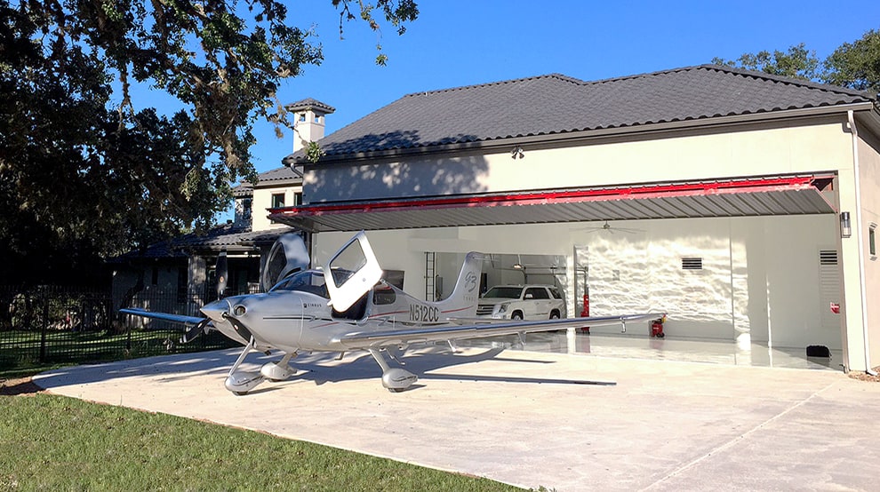 Schweiss bifold fold up door installed on Texas hangar home shown open with plane parked out front Schweiss bifold fold up door installed on Texas hangar home shown open with plane parked out front