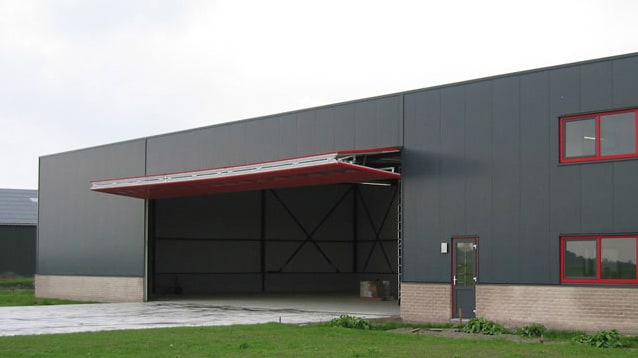Red Schweiss bifold commercial door installed on a commercial building shown open Red Schweiss bifold commercial door installed on a commercial building shown open