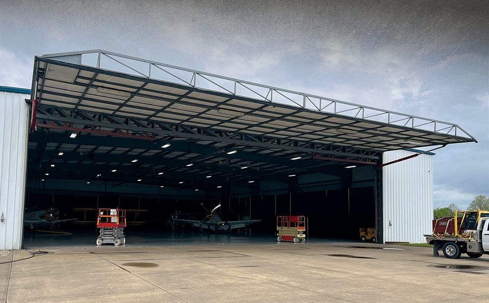 New York hydraulic door by Schweiss installed on hangar with plane inside